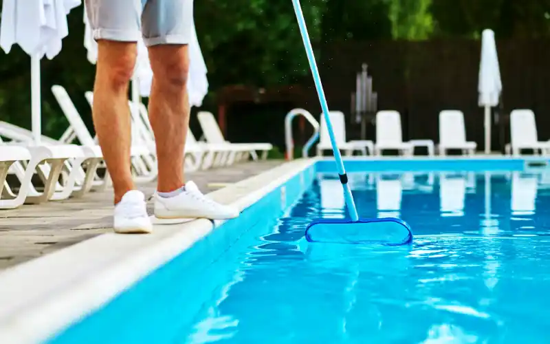 A service person cleaning the swimming pool and looking busy