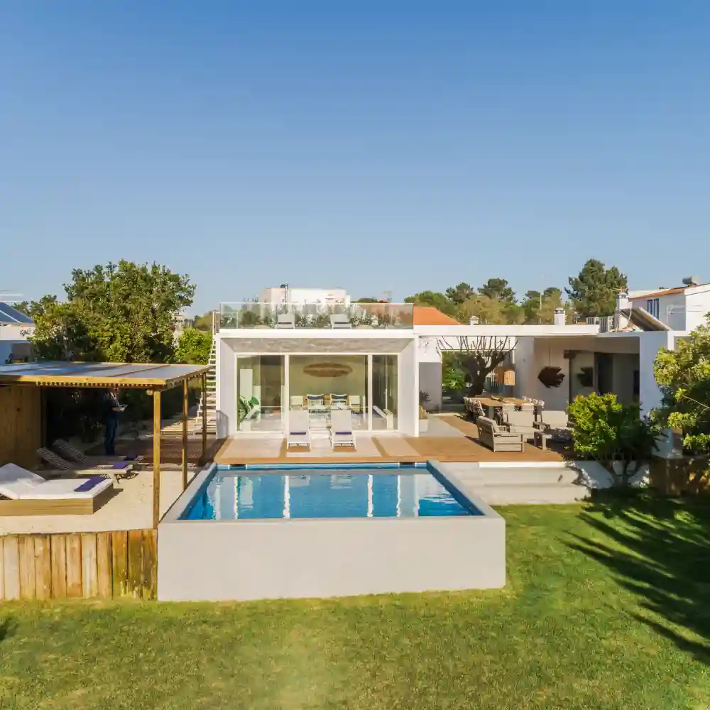 Modern villa at sunset with a pool reflecting the orange sky