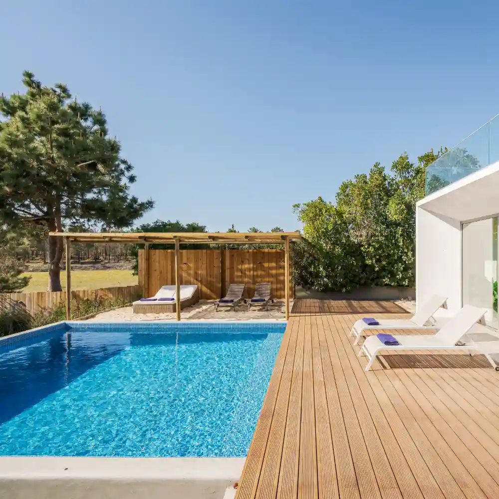 Modern villa with a wooden deck and swimming pool under a clear blue sky