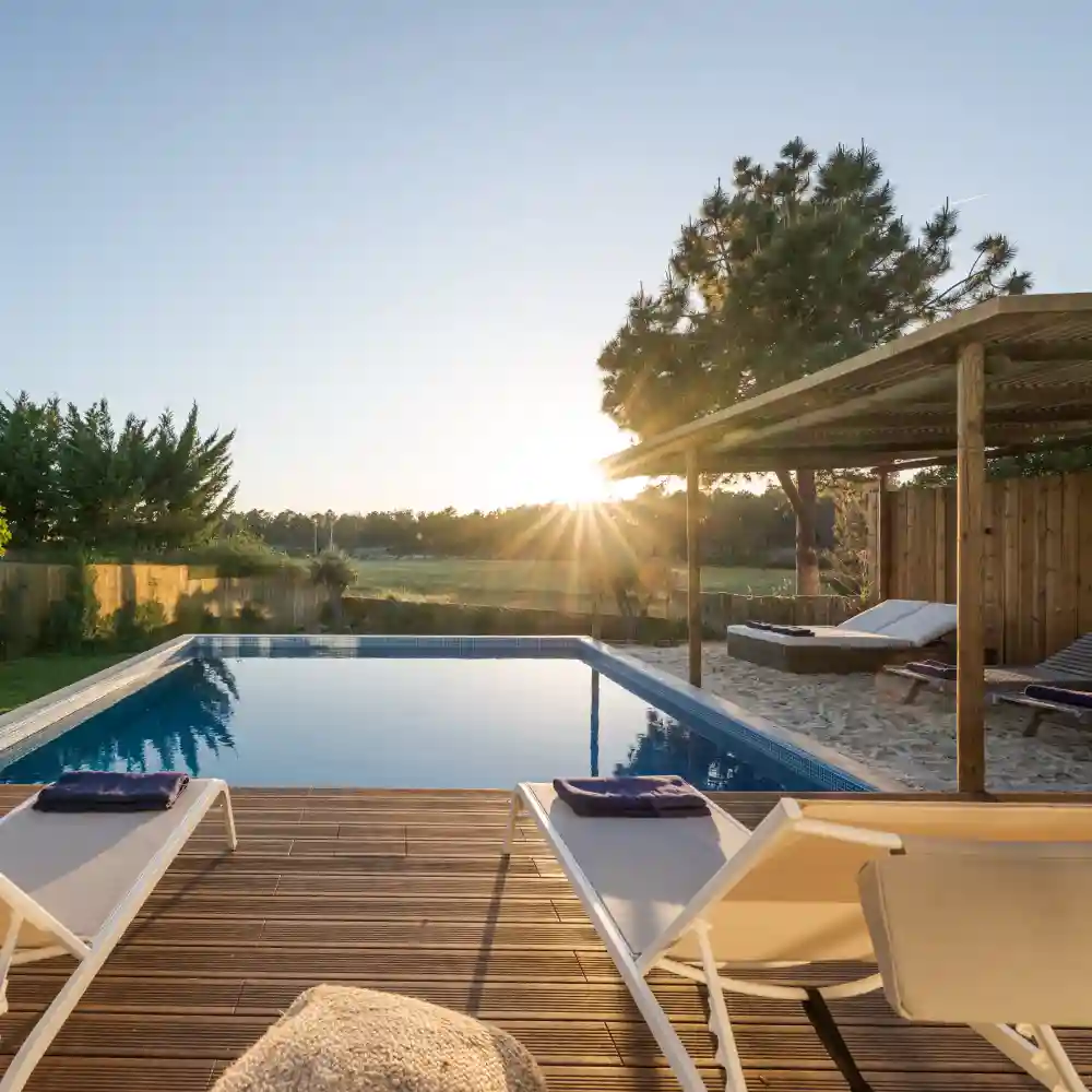 White modern house with a green lawn and swimming pool at sunset